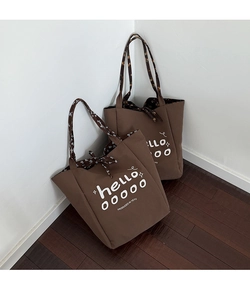 Detail view of large canvas tote bags featuring floral patterned handles and text print