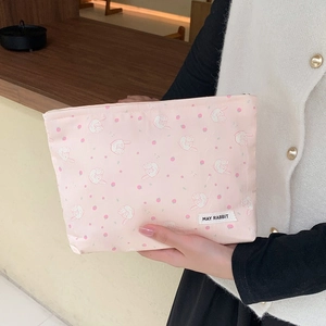 Close-up of pink cosmetic bag with strawberry and rabbit print and white logo label