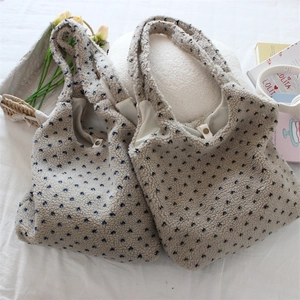 Detail of fleece tote bag with blue floral print and magnetic clasp on white bedding