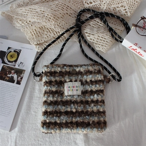 Close-up of plush striped crossbody bag texture with Mayrabbit label and woven strap