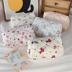 Quilted cotton makeup bag with cute cartoon prints and zipper, set on a cozy white cloth