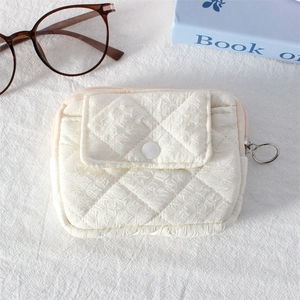 Close-up of cream quilted mini pouch featuring rhombus texture and metal ring zipper