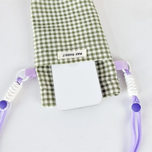 Detail of green plaid phone bag showing adjustable strap and inner storage space