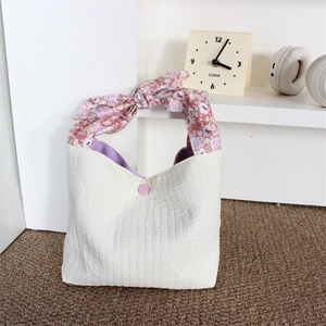 Detail of cream pleated tote bag with pink floral bow handle and button closure