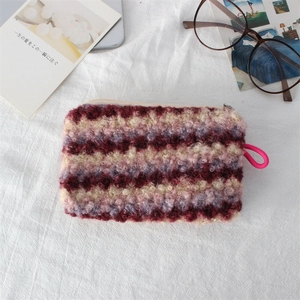 Macro shot of striped Sherpa cosmetic bag with fuzzy texture and pink woven puller