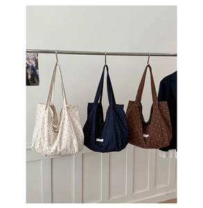 Detailed view of three polka dot canvas tote bags in white, navy, and dark brown colors