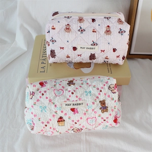 Close-up of quilted fabric with cartoon bear prints and brand label on two cosmetic bags