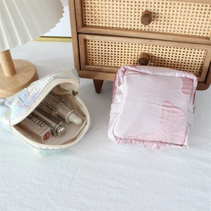 Detail of portable jacquard cosmetic pouches with floral and bow patterns and zipper closure