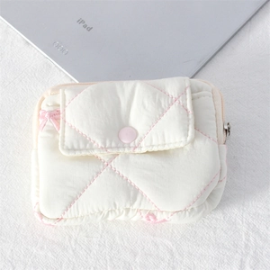 Detail view of a quilted mini coin purse with pink diamond stitching and bow accent