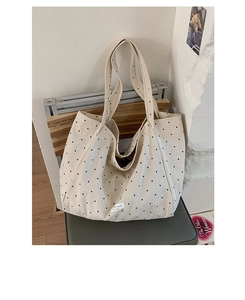 Close-up of beige canvas tote bag with black polka dots and white fabric label detail