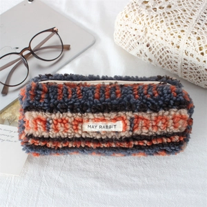 Detail of plush striped pencil case with zipper and white label in a cozy setting