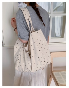 Detailed shot of spacious polka dot canvas tote bag worn by a model in a natural setting