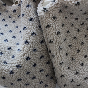 Close-up of sherpa fleece tote bag featuring thick plush texture and navy blue polka dots