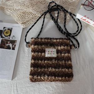 Close-up of brown striped plush fabric texture and shoulder strap on messenger bag