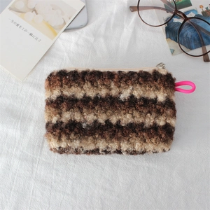 Detail of striped sherpa fleece makeup bag with pink rope zipper pull and soft texture