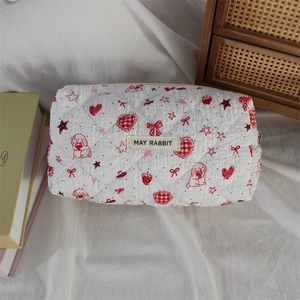 Close-up of quilted cosmetic bag with red heart and rabbit patterns and zipper closure