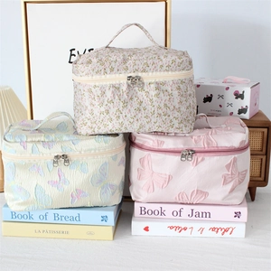 Close-up of floral jacquard makeup bags with textured patterns and gold dual zippers