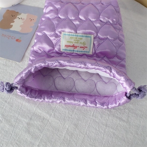 Detail of purple quilted heart camera bag with silk finish and drawstring closure