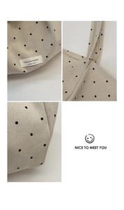 Detail of polka dot canvas tote showing reinforced stitching and branded fabric label