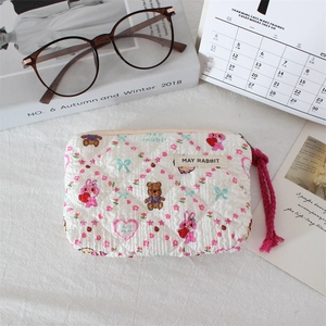 Detail of white quilted cosmetic bag with cute bunny bear prints and woven zipper pull