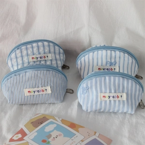 Detail of mini shell pouches with bow embroidery and striped checkered cotton fabric