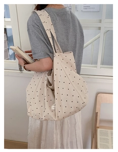 Detail of polka dot canvas tote bag showing wide shoulder strap and side profile