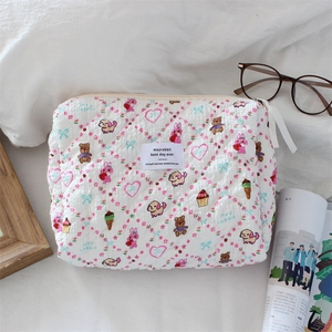 Detailaufnahme der gesteppten Cartoon-Kosmetiktasche mit Bärenprint und Markenlabel