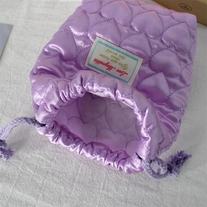 Macro shot of purple quilted drawstring pouch with heart pattern and white label detail