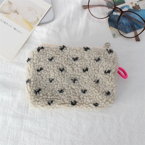 Close-up of cream faux shearling makeup bag with black polka dots and pink lanyard