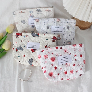 Detailed view of four quilted cotton cosmetic bags with assorted cute cartoon patterns