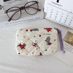 Detail of quilted cotton dog print makeup bag with purple zipper strap and brand label