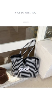 Close-up of the grey and black striped tote bag featuring a bold white good letter print