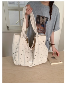 Close-up of cream canvas tote bag with black polka dots and wide shoulder strap
