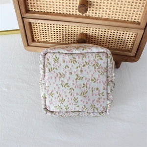 Close-up of a floral fabric storage bag with embroidery and silver metal zipper detail