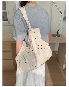 Detailed view of large canvas tote bag with polka dot pattern and woven brand label