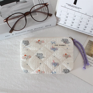 Detailed texture of white quilted mini bag with cute cartoon elephant prints and purple zip puller