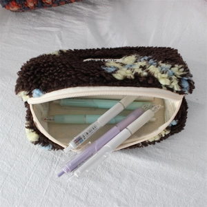 Close-up of floral plush pencil case opening with colorful pens and soft fleece texture