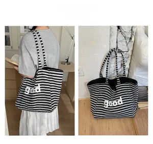 Close-up of a striped canvas tote bag featuring white 'good' lettering and knit texture