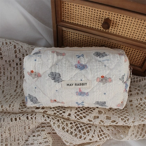 Detail of white quilted cosmetic bag featuring cute cartoon elephant print and soft texture