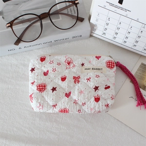 Detail of a quilted strawberry pouch with a zipper closure and a May Rabbit fabric label