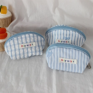 Detailed view of three mini embroidered bow coin purses with checkered and striped fabric patterns