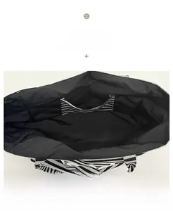 Close-up of the spacious black interior lining and striped open inner pocket of the tote bag
