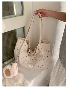 Detailed texture of high-capacity polka dot canvas tote bag with woven logo label