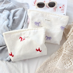 Detail of satin jacquard makeup bag with horse embroidery and MAY RABBIT label