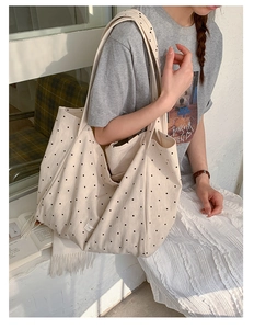 Detailed close-up of large canvas tote bag with black polka dots on cream background