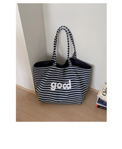 Close-up of the thick knitted texture and bold 'good' text on the striped tote bag