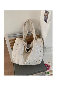 Detail of beige canvas tote bag with black polka dots and durable woven shoulder straps