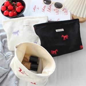 Detail of satin jacquard makeup bag with pony embroidery and inner storage space
