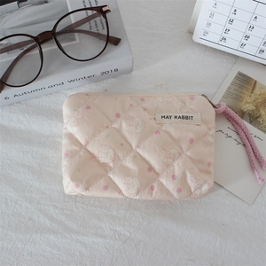 Close-up of pink quilted makeup pouch featuring rabbit and strawberry floral patterns