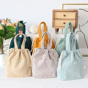 Collection of corduroy drawstring handbags in five colors displayed with floral decor